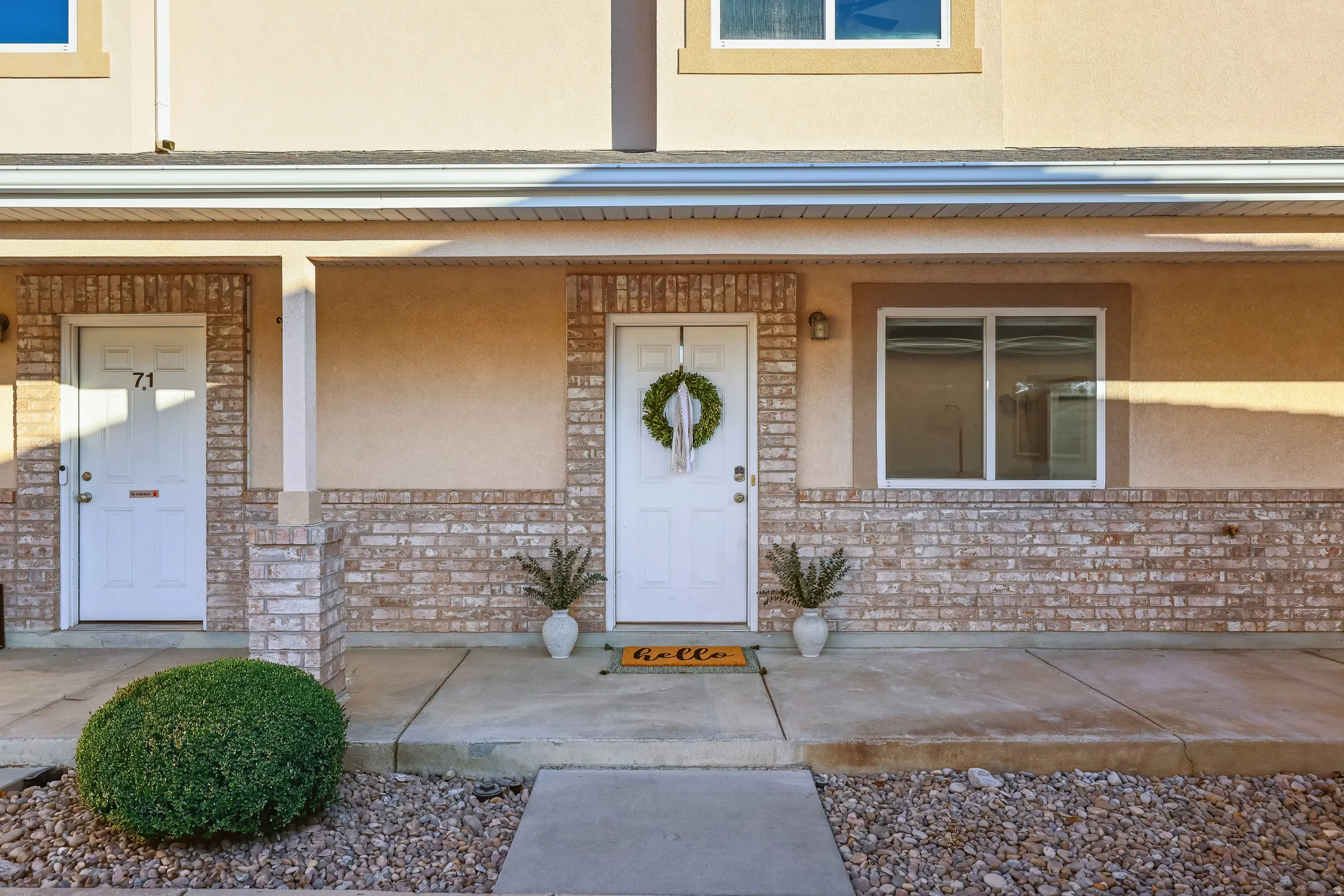 Doorway to property featuring a porch, stucco siding, and brick siding