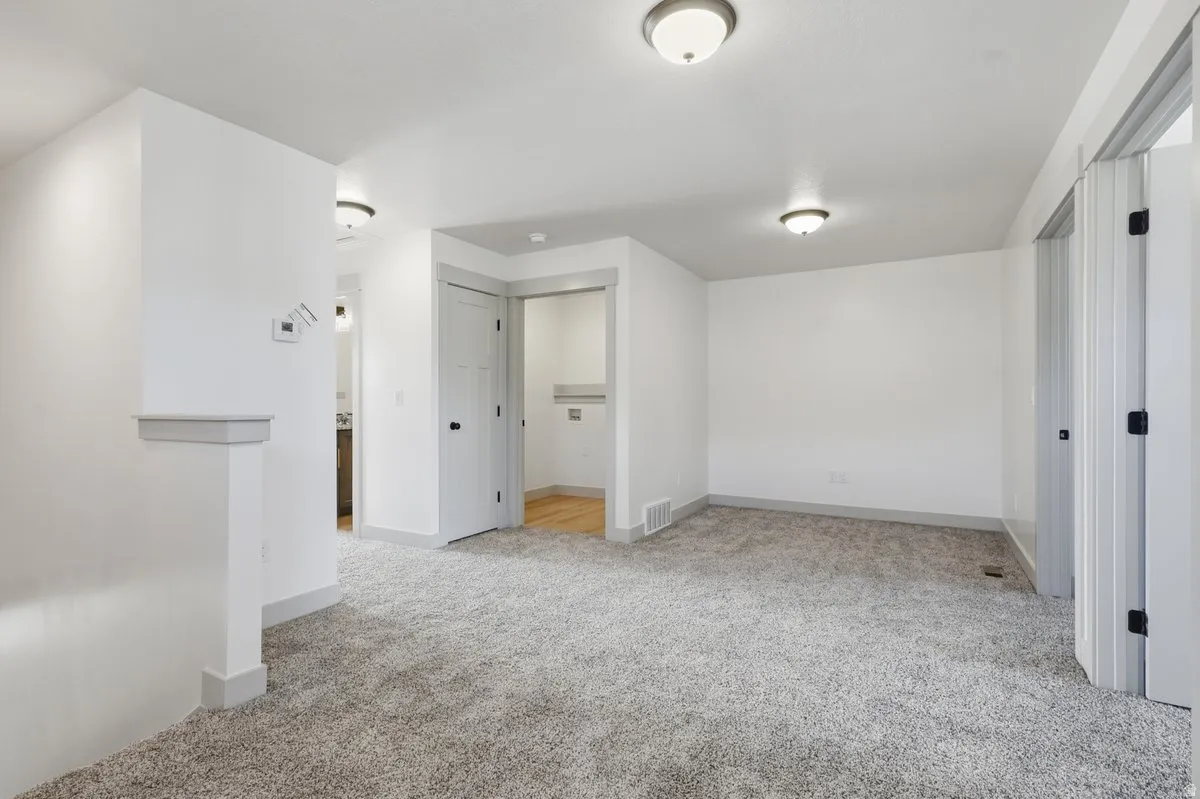 Unfurnished bedroom with light carpet and baseboards