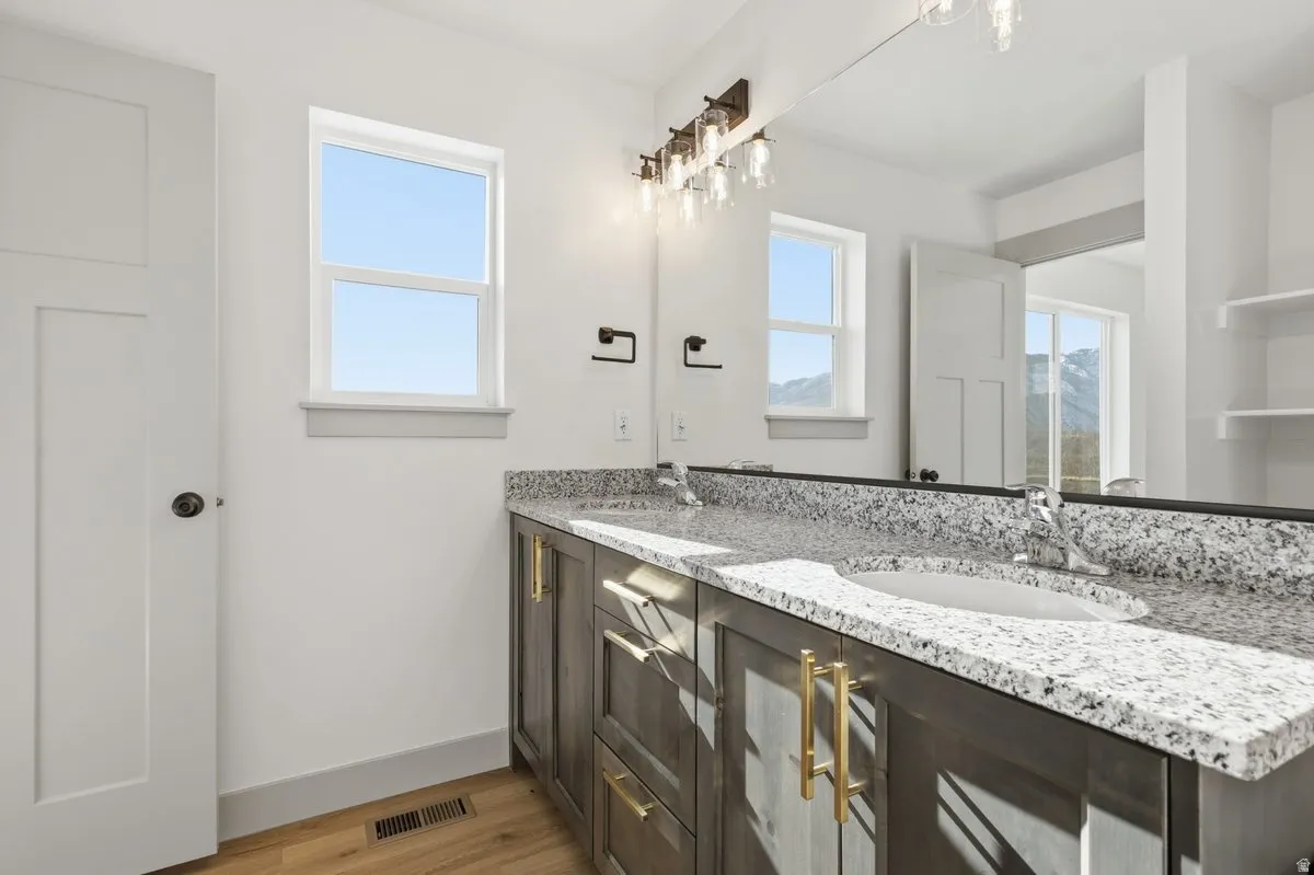 Full bath featuring double vanity and light wood-type flooring