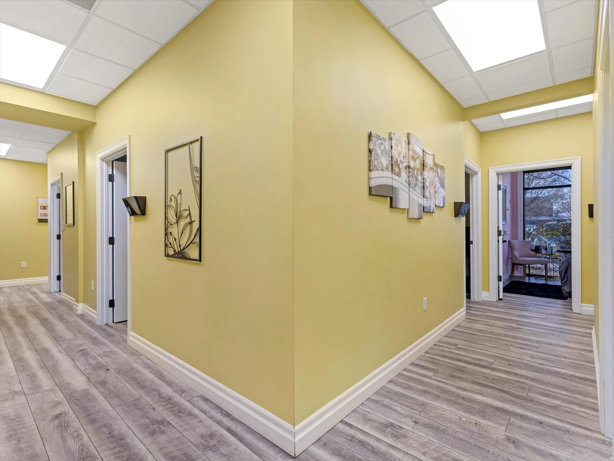 Corridor with a drop ceiling and wood finished floors