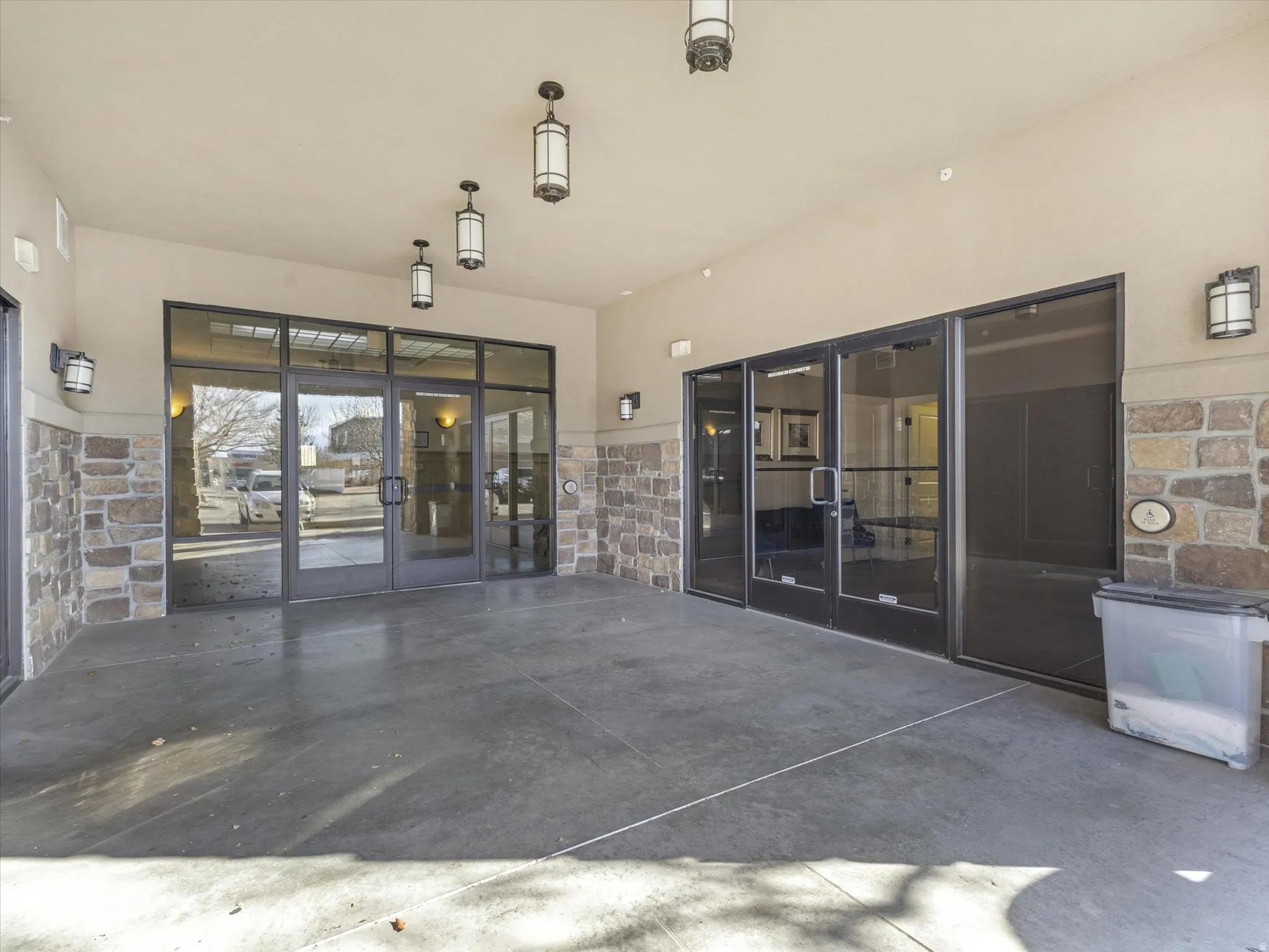 Entrance to property featuring stone siding, a patio, and stucco siding