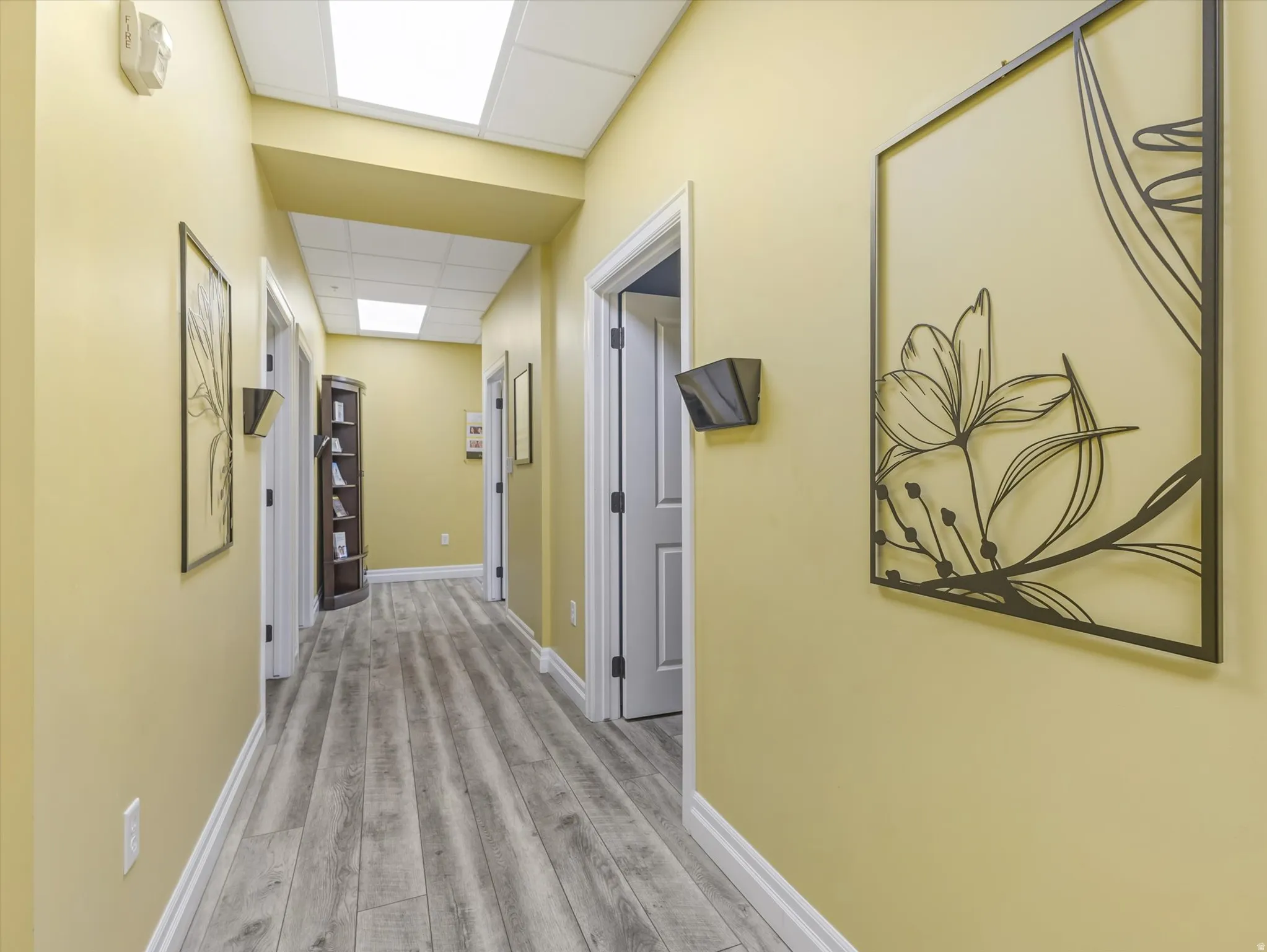 Hallway featuring a paneled ceiling and light wood finished floors