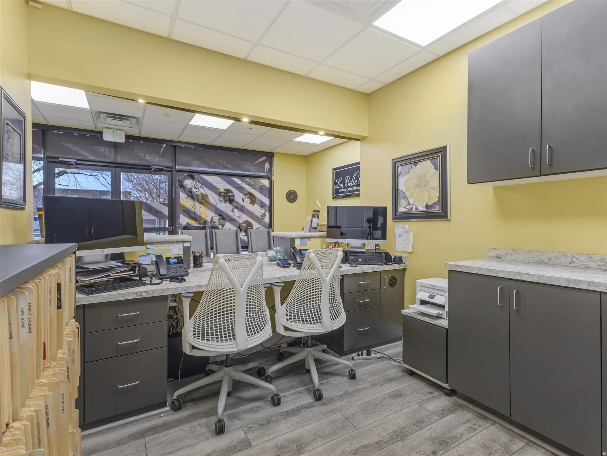 Office space featuring a drop ceiling, built in desk, and radiator heating unit