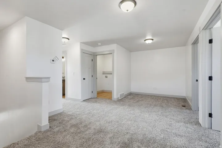 Unfurnished bedroom with light carpet and baseboards