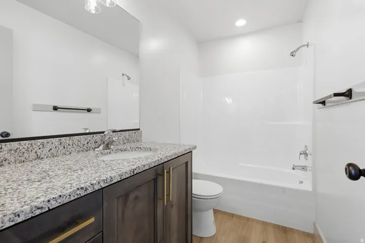 Bathroom with vanity, light wood finished floors, shower / washtub combination, and recessed lighting