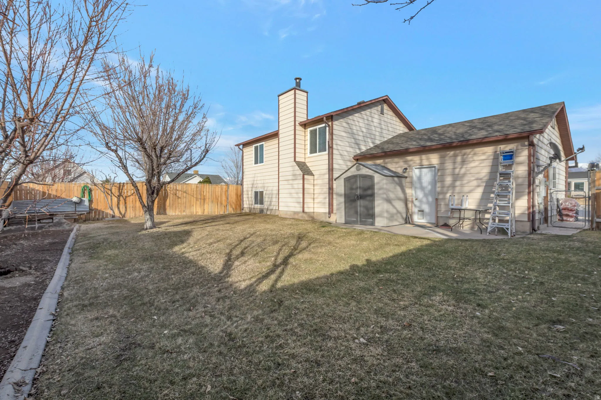 Rear view of property featuring a fenced backyard, a chimney, and roof with shingles