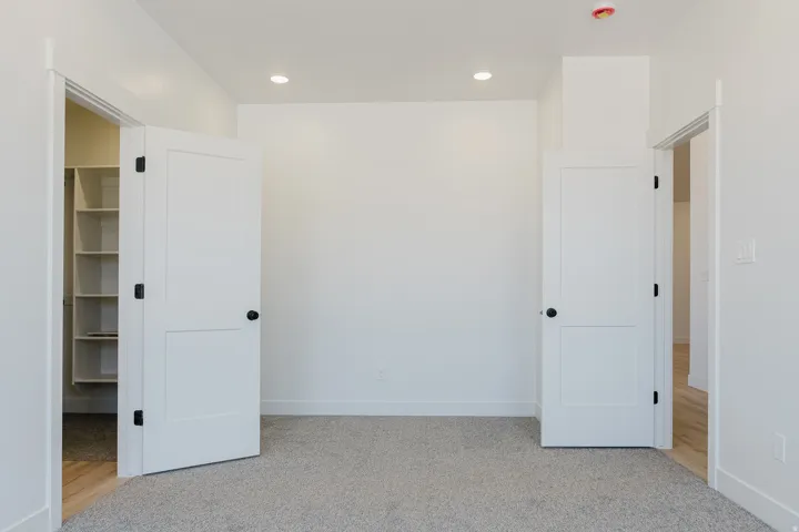 Unfurnished bedroom featuring light colored carpet, a walk in closet, and recessed lighting