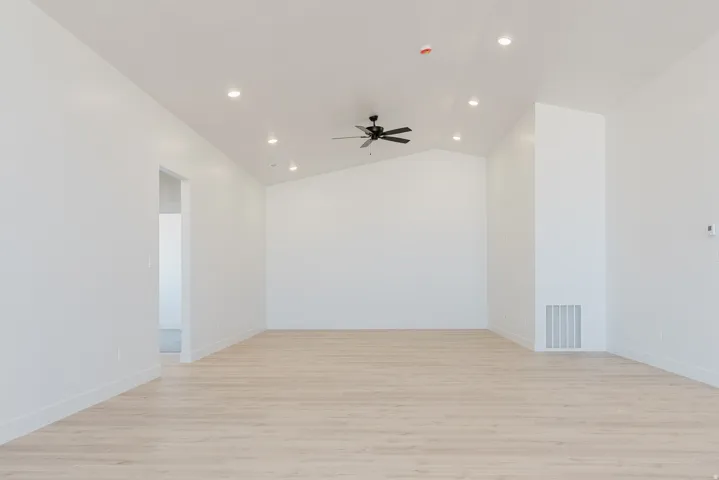 Spare room featuring light wood-style floors, lofted ceiling, a ceiling fan, and recessed lighting