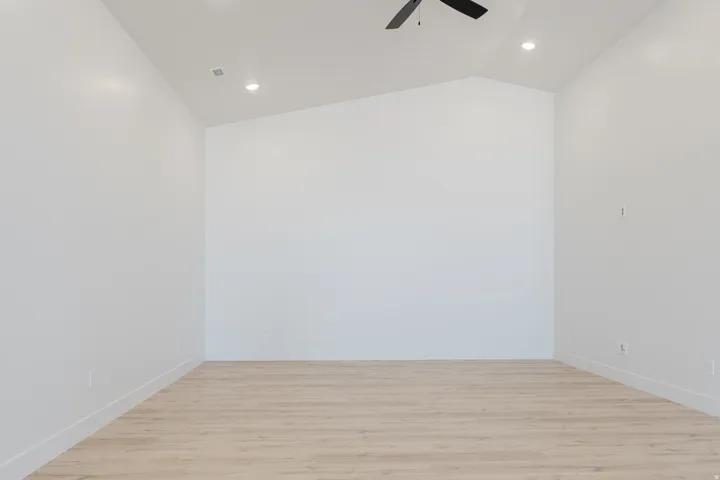 Spare room featuring light wood-style flooring, ceiling fan, vaulted ceiling, and recessed lighting