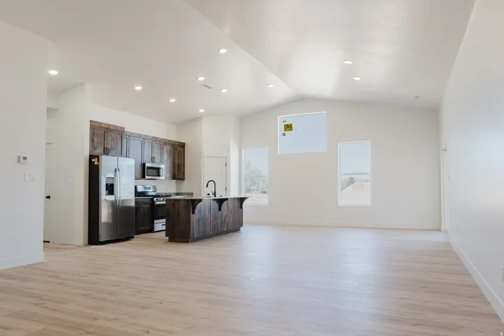 Kitchen with dark wood finish cabinetry, a kitchen breakfast bar, open floor plan, stainless steel appliances, and a center island with sink