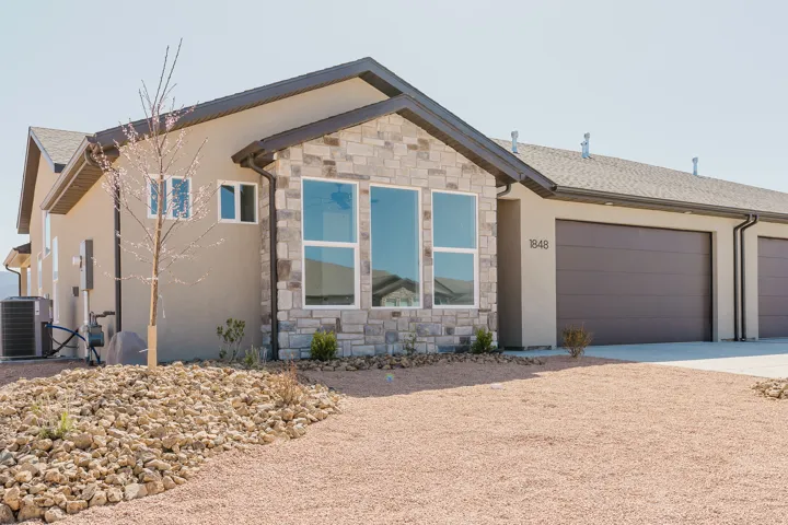 Ranch-style home with stone siding, driveway, and stucco siding