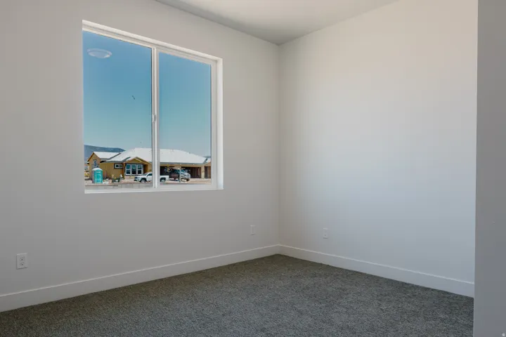 Spare room featuring baseboards and dark colored carpet