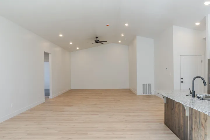 Kitchen featuring recessed lighting, light stone counters, light wood-type flooring, lofted ceiling, and ceiling fan