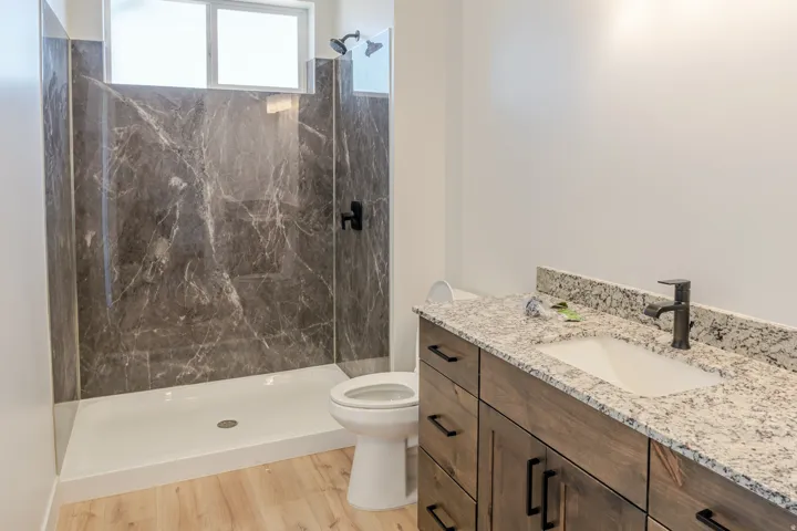 Bathroom featuring vanity, a marble finish shower, and light wood-type flooring