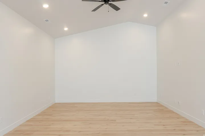 Spare room with light wood-type flooring, a ceiling fan, vaulted ceiling, and recessed lighting