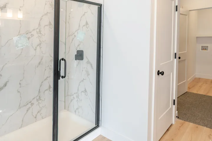 Full bathroom with light wood-type flooring and a marble finish shower