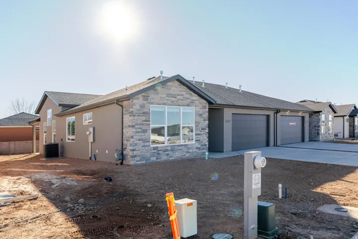 Ranch-style home with stone siding, stucco siding, and concrete driveway