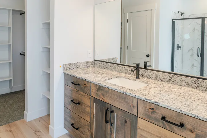Full bathroom featuring vanity, a marble finish shower, a spacious closet, and light wood finished floors