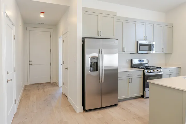 Kitchen with stainless steel appliances, light wood-type flooring, gray cabinets, and light stone counters