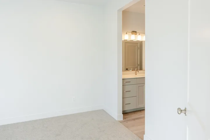Unfurnished bedroom featuring ensuite bathroom and light carpet