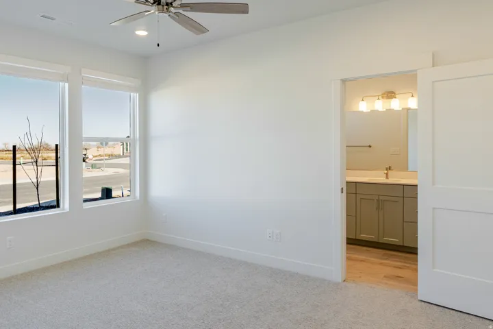 Unfurnished bedroom featuring light colored carpet, ensuite bath, a ceiling fan, and recessed lighting