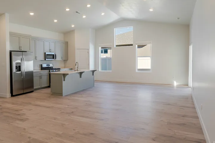 Kitchen featuring gray cabinetry, a high ceiling, stainless steel appliances, a breakfast bar area, and a center island with sink