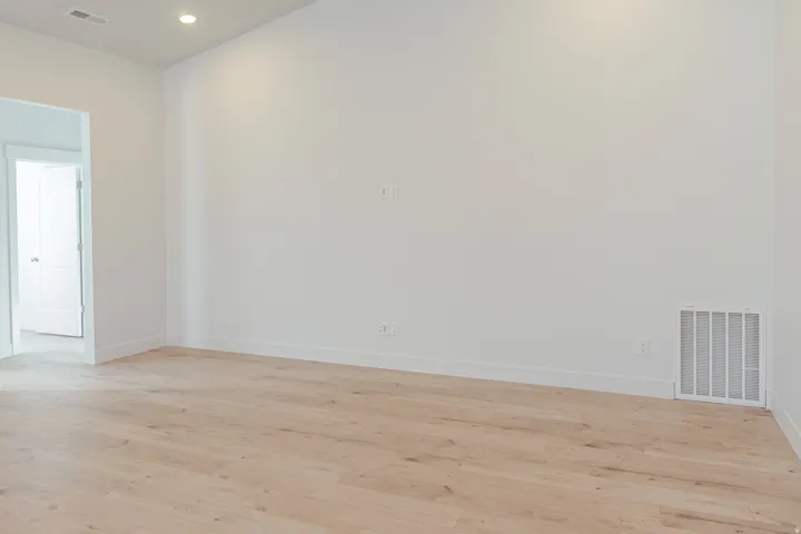 Empty room with light wood-style floors and recessed lighting