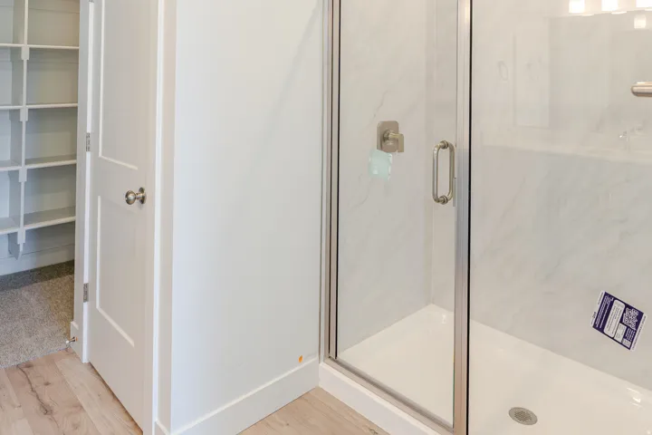 Full bathroom featuring a shower stall, light wood-type flooring, and a spacious closet