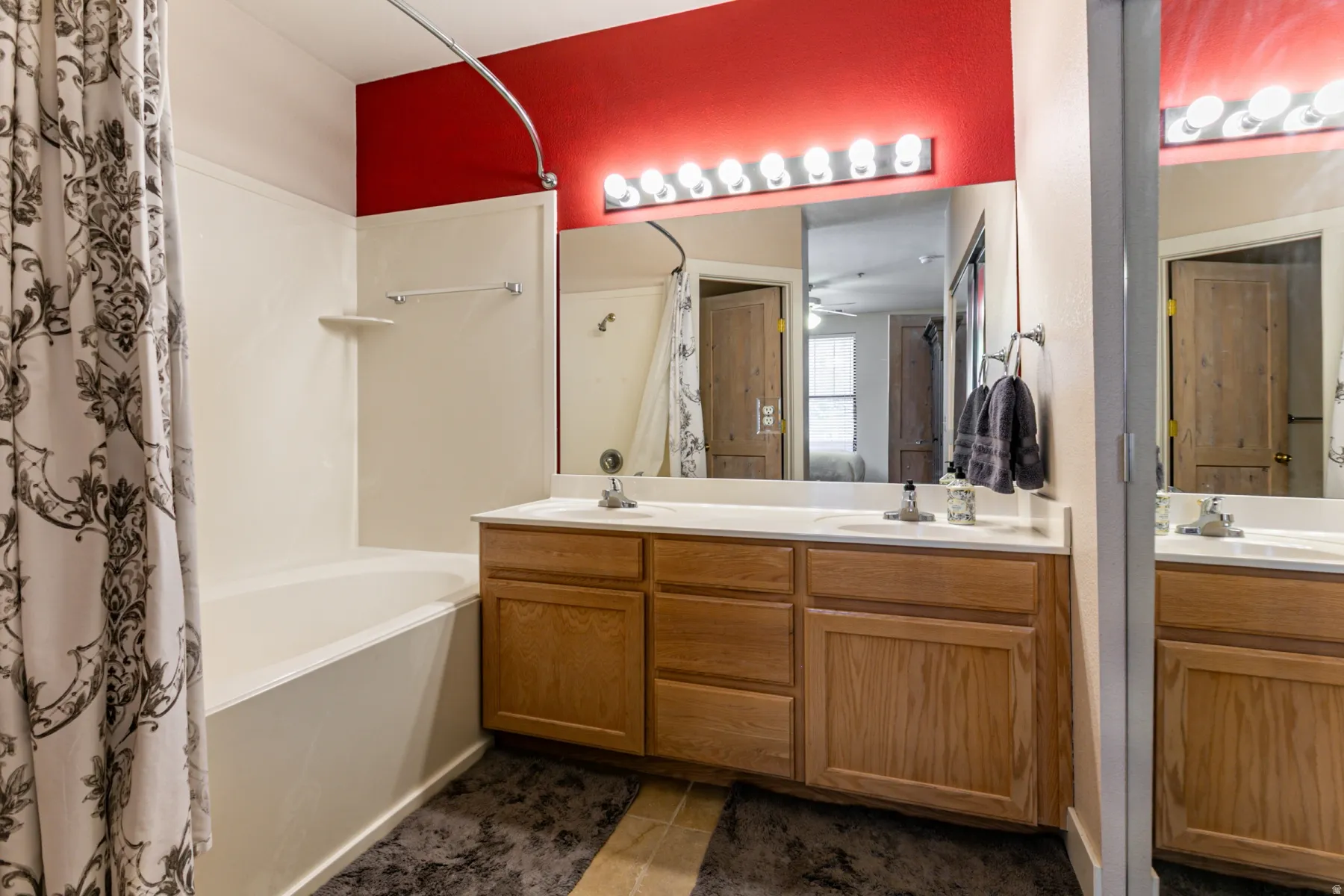 Bathroom with double vanity, shower / tub combo, and dark tile patterned floors