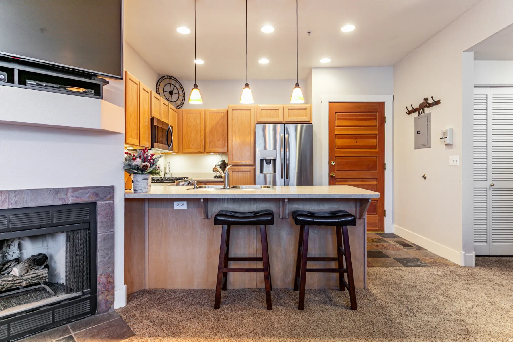 Kitchen featuring a peninsula, light countertops, a breakfast bar, hanging light fixtures, and a fireplace