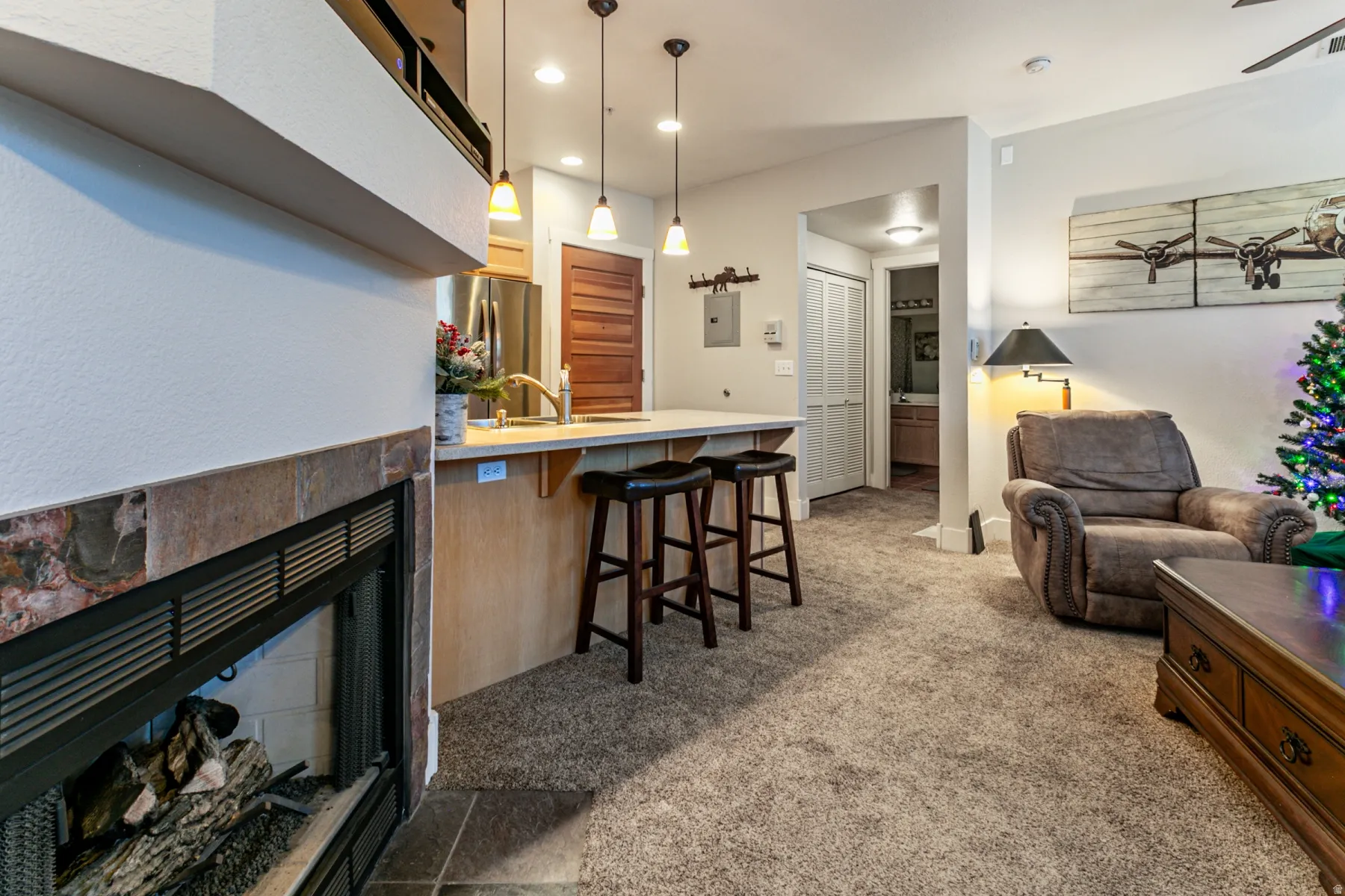 Living area featuring a tile fireplace, light carpet, recessed lighting, and electric panel
