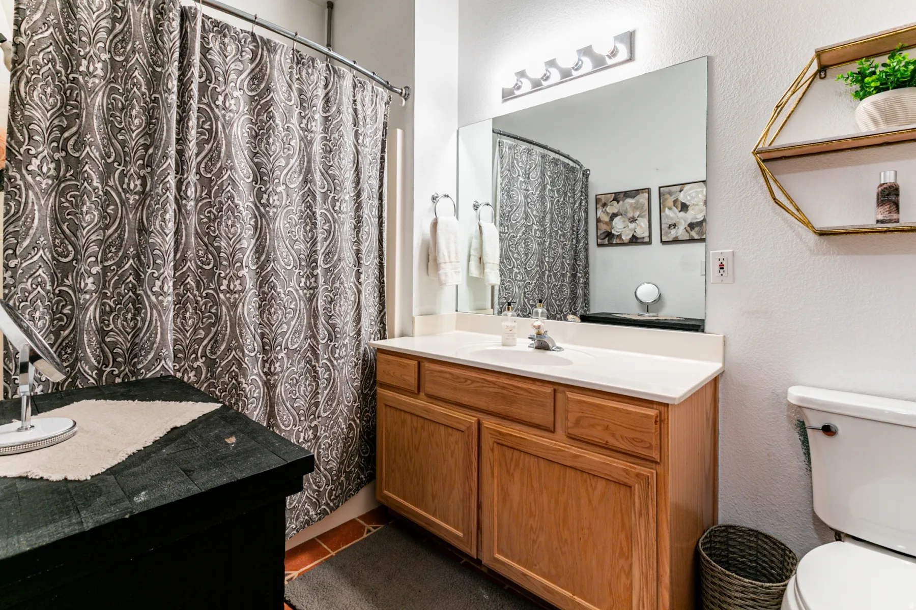 Full bathroom with a textured wall, vanity, and a shower with curtain