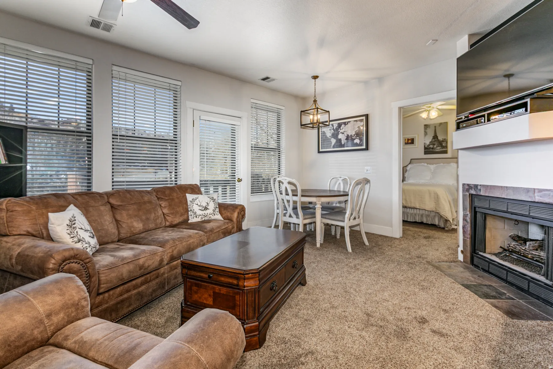 Carpeted living room with a ceiling fan and a tile fireplace