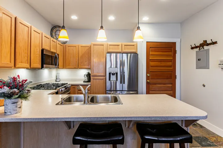 Kitchen with stainless steel appliances, a kitchen breakfast bar, a peninsula, hanging light fixtures, and electric panel