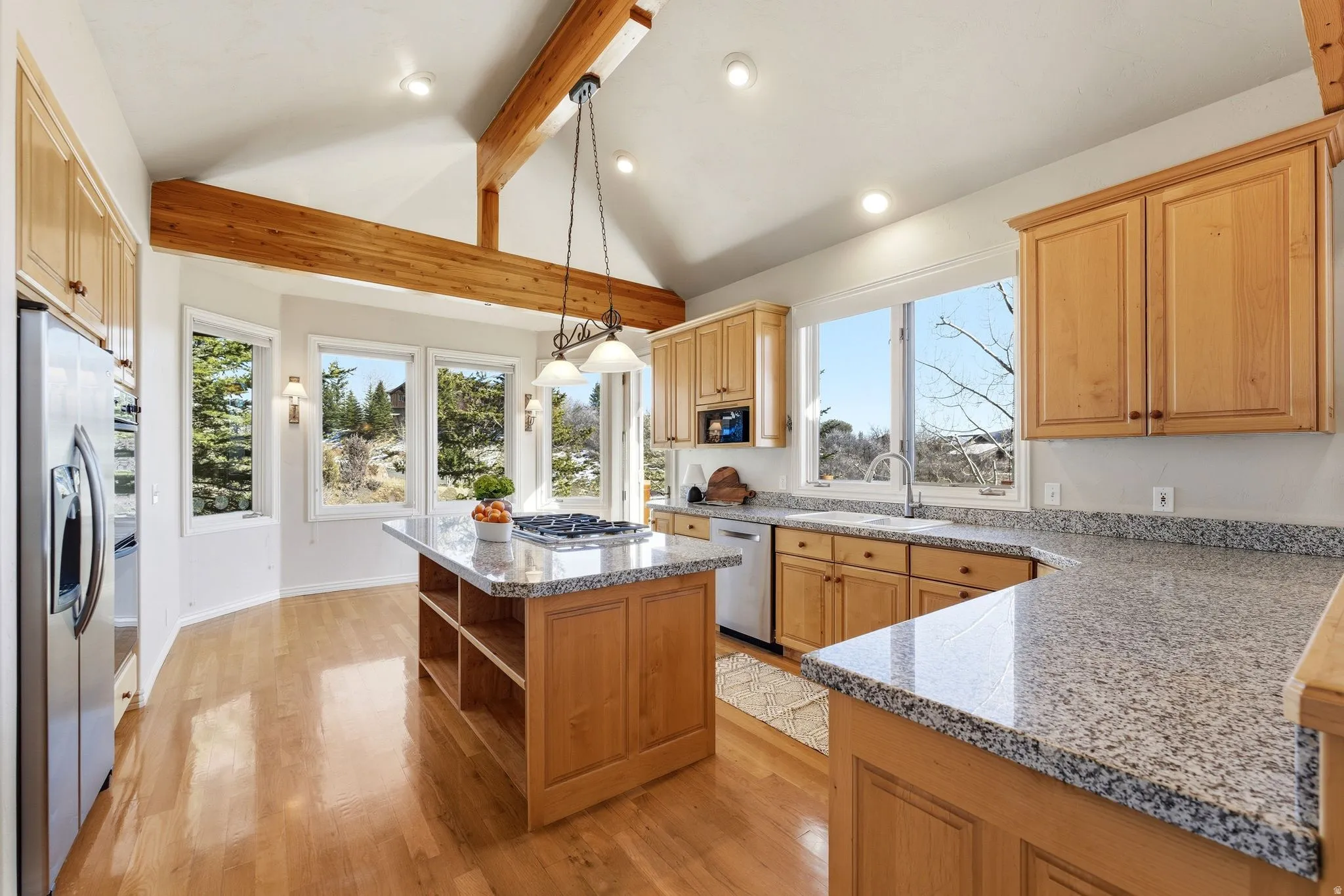 Kitchen with light stone counters, a center island, light wood finished floors, open shelves, and pendant lighting