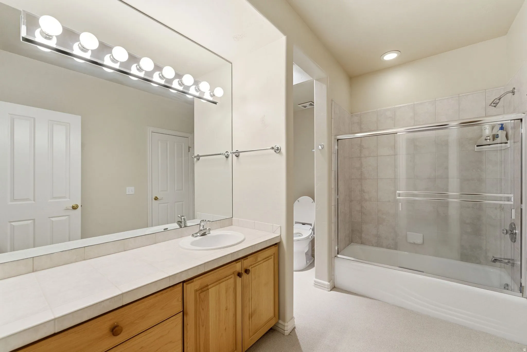 Bathroom featuring vanity and bath / shower combo with glass door
