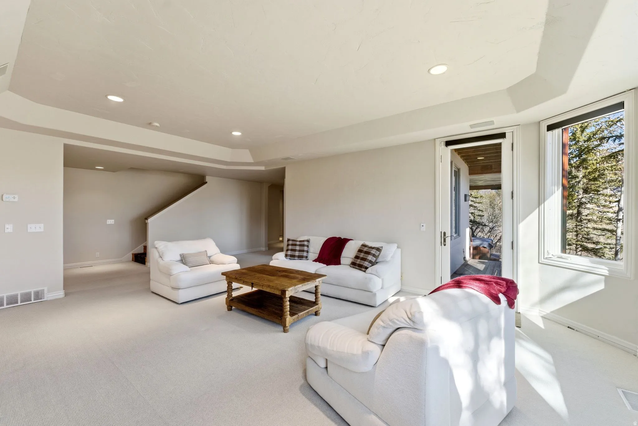 Carpeted living area featuring a raised ceiling and recessed lighting