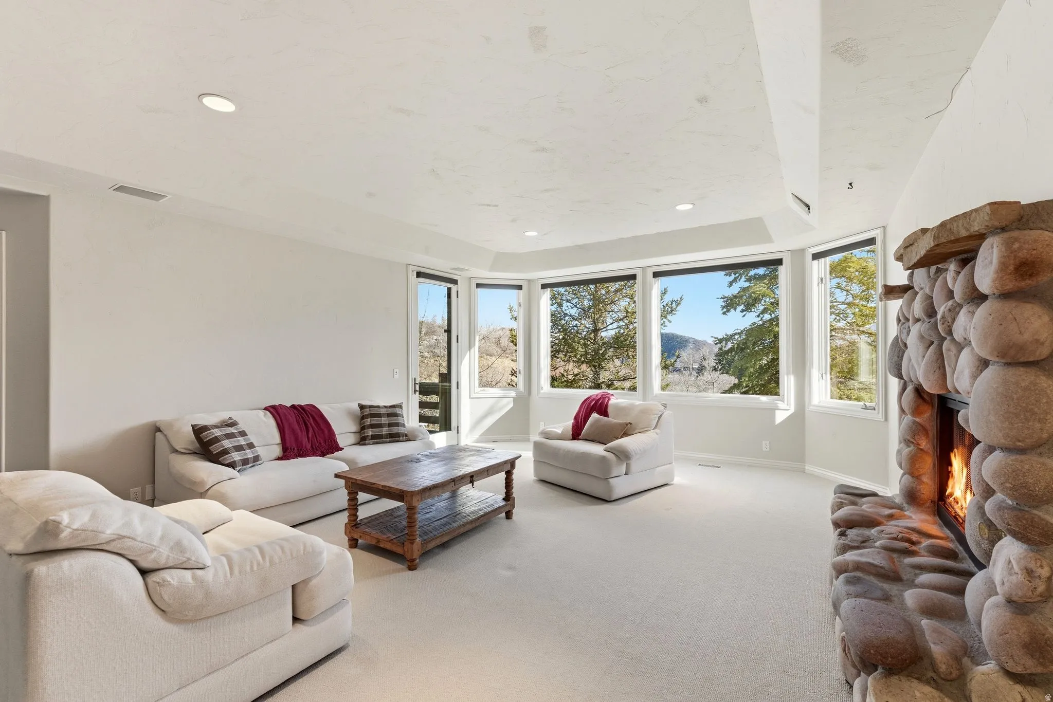 Living room with carpet, a fireplace, recessed lighting, a raised ceiling, and a mountain view