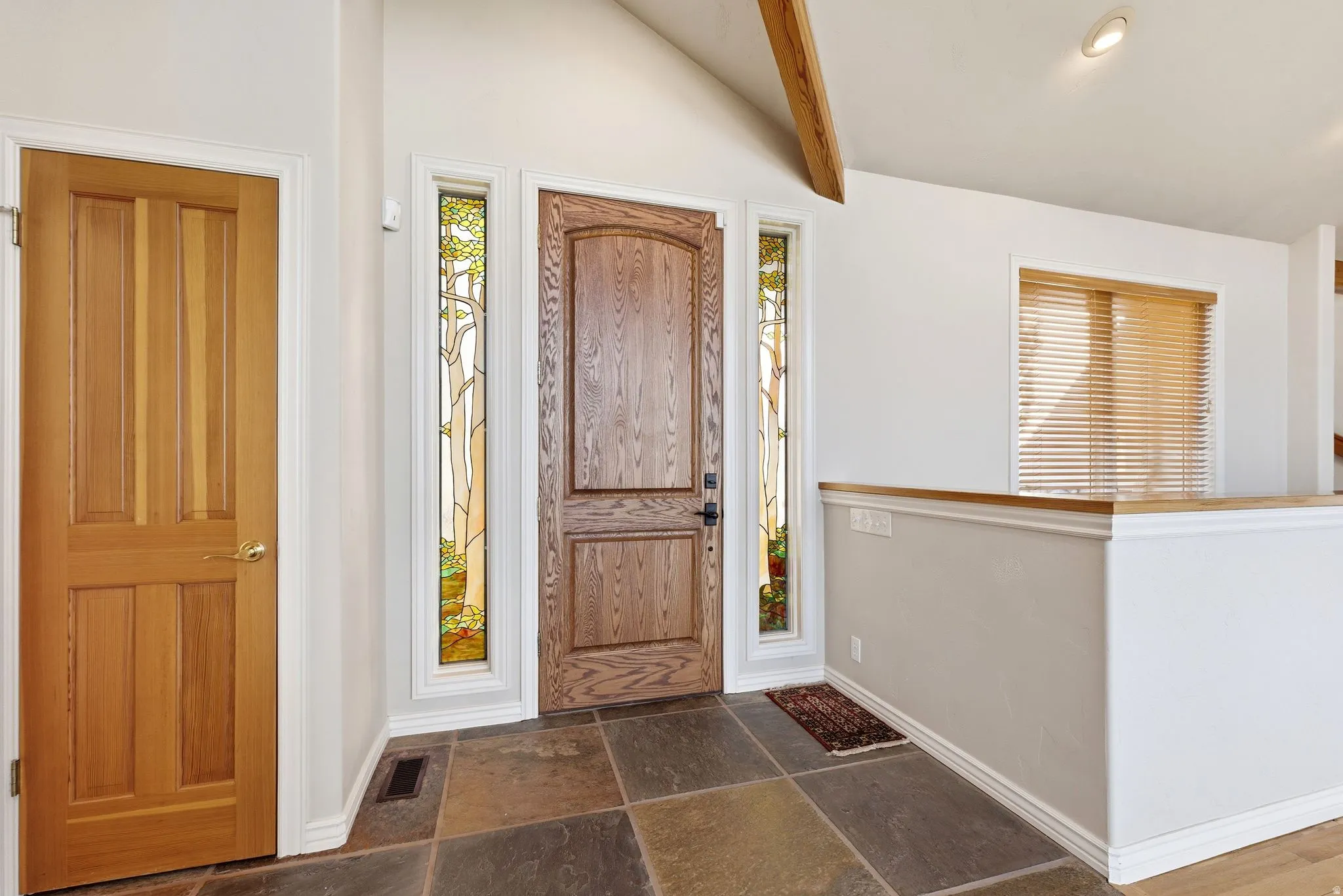 Entryway featuring stone tile flooring and lofted ceiling with beams