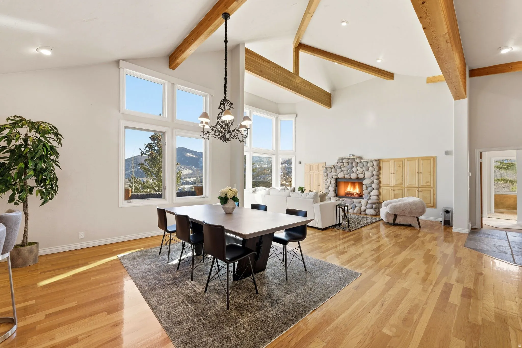 Dining area featuring a fireplace, light wood-style floors, a mountain view, lofted ceiling, and hanging lights