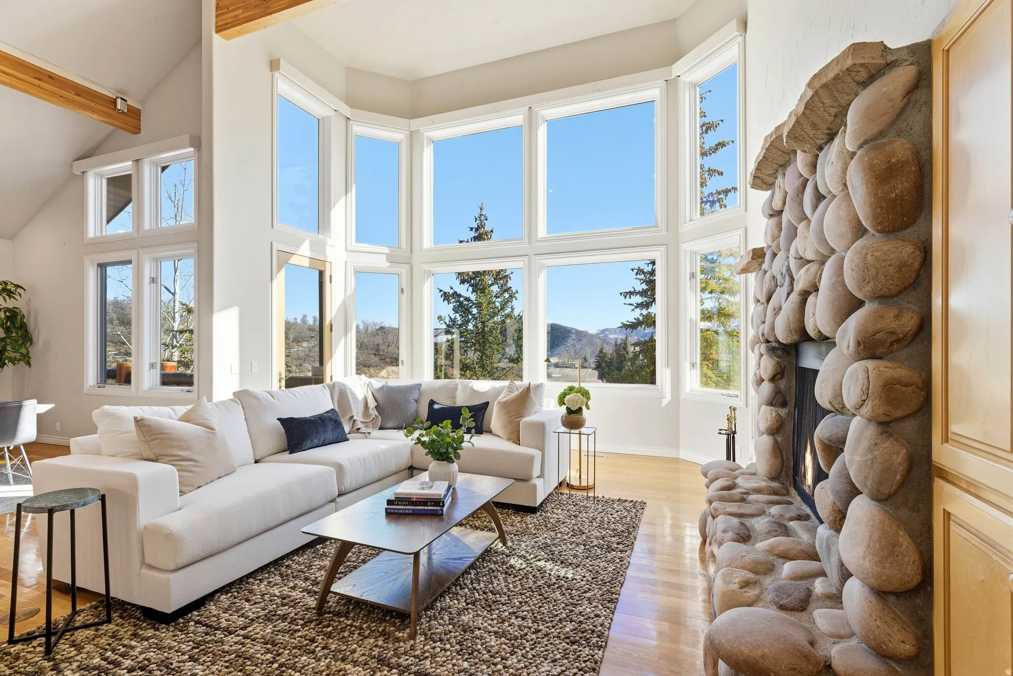 Living room with light wood-type flooring, a mountain view, a fireplace, and vaulted ceiling