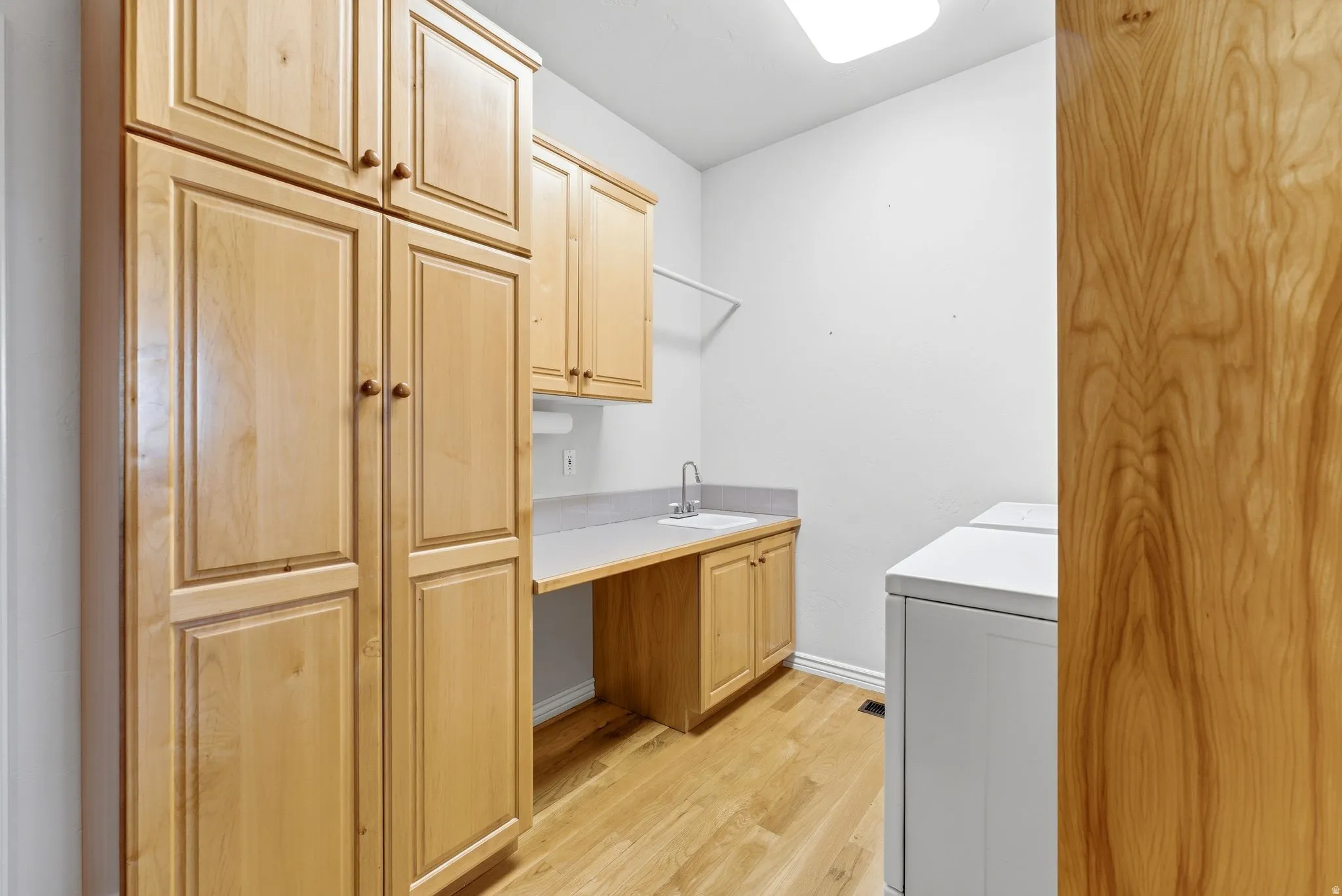 Laundry area featuring washer / dryer, cabinet space, and light wood-style floors