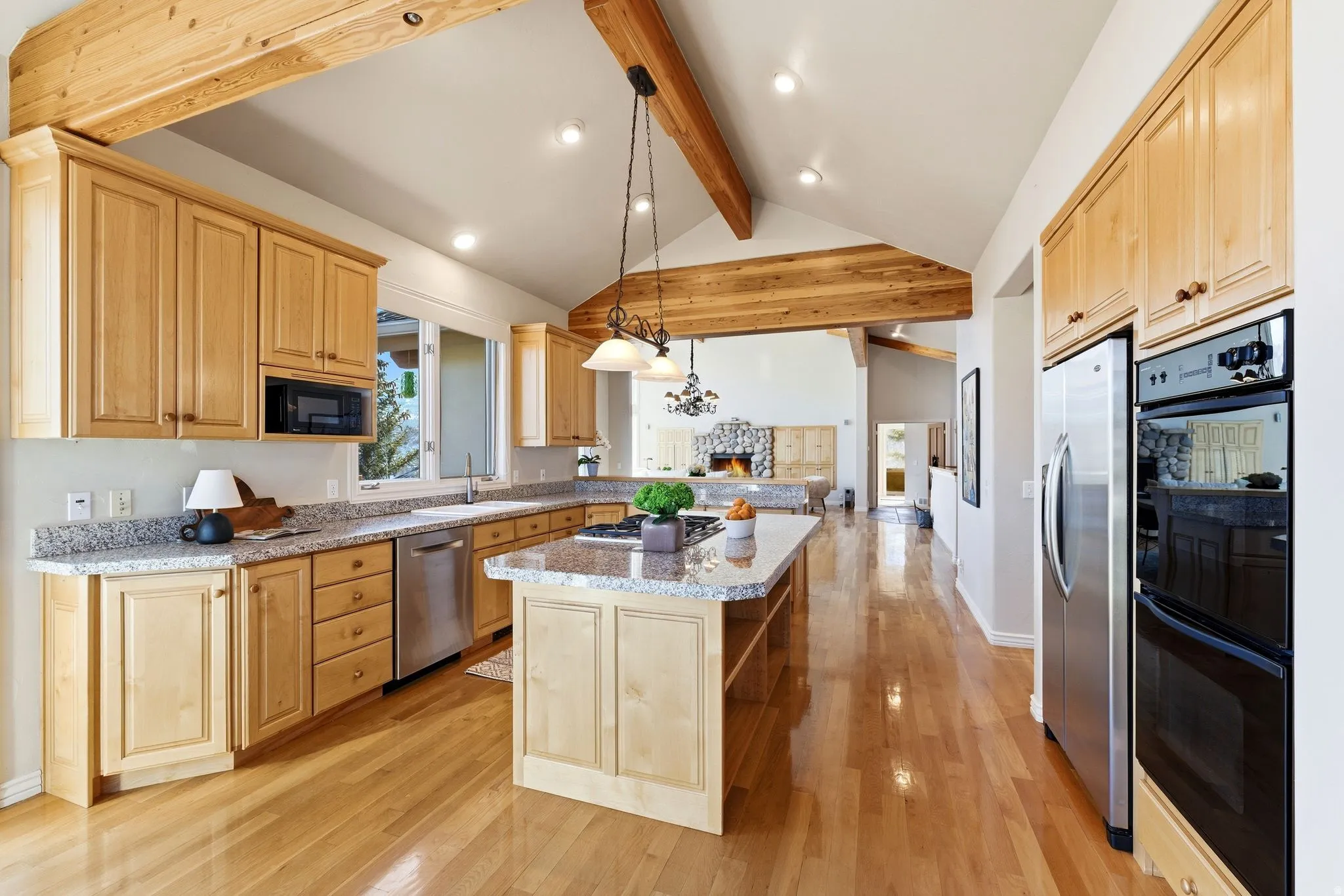 Kitchen with stainless steel appliances, pendant lighting, light wood finish cabinets, and light wood finished floors