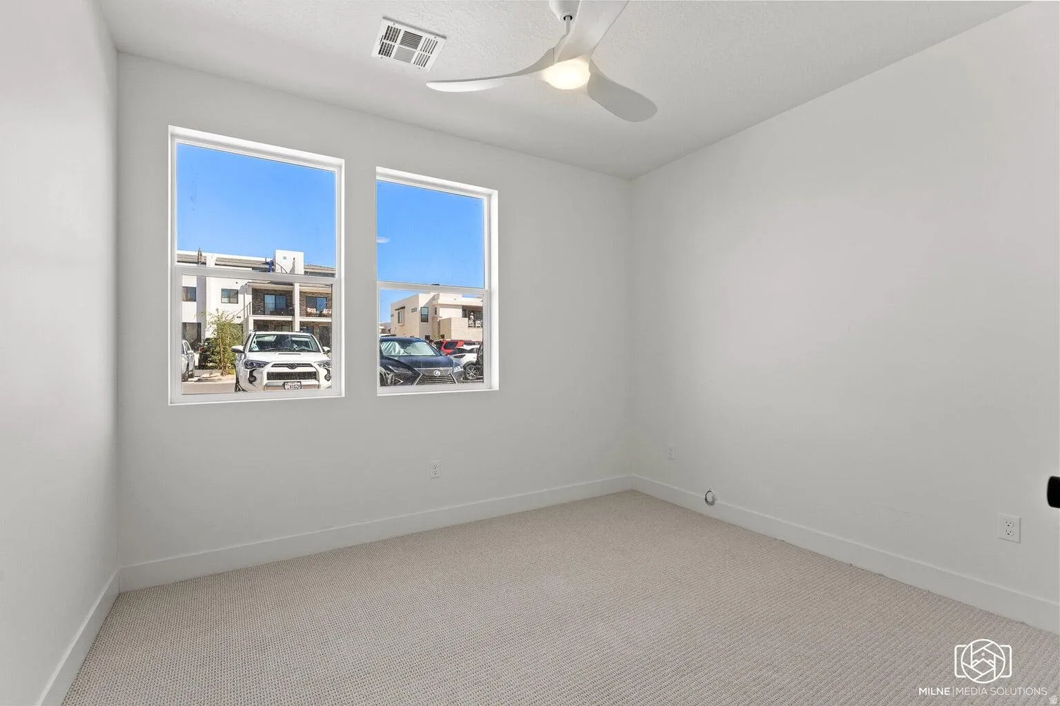 Carpeted empty room with a ceiling fan and baseboards