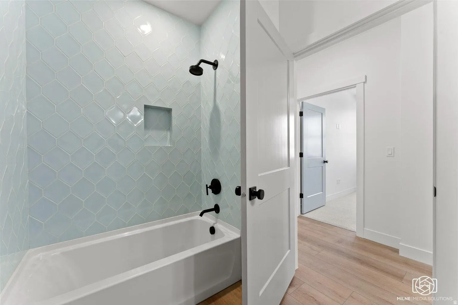 Full bath featuring  shower combination and light wood-style flooring