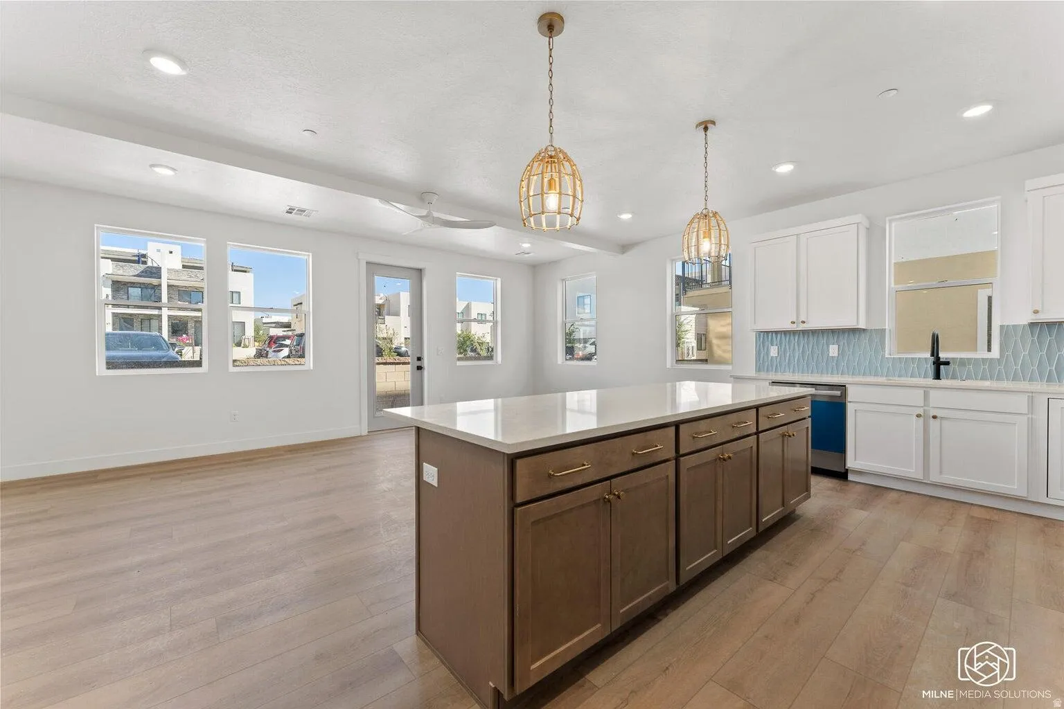 Dual tone kitchen featuring dual tone cabinets, decorative backsplash, light wood-style floors, a center island, and ceiling fan