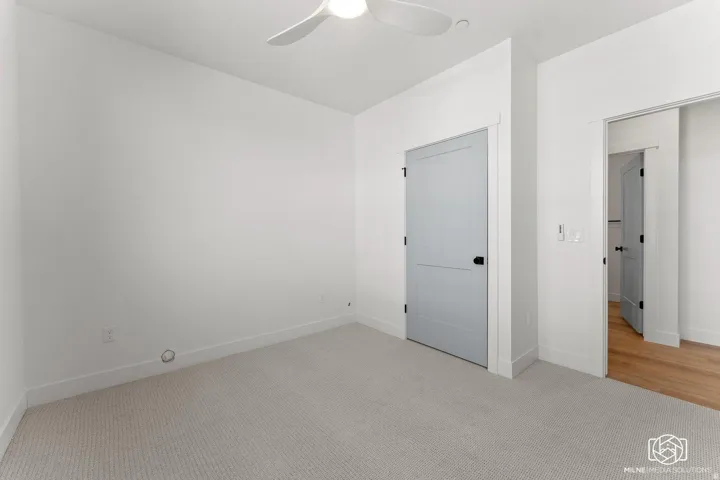 Unfurnished bedroom with light carpet and ceiling fan