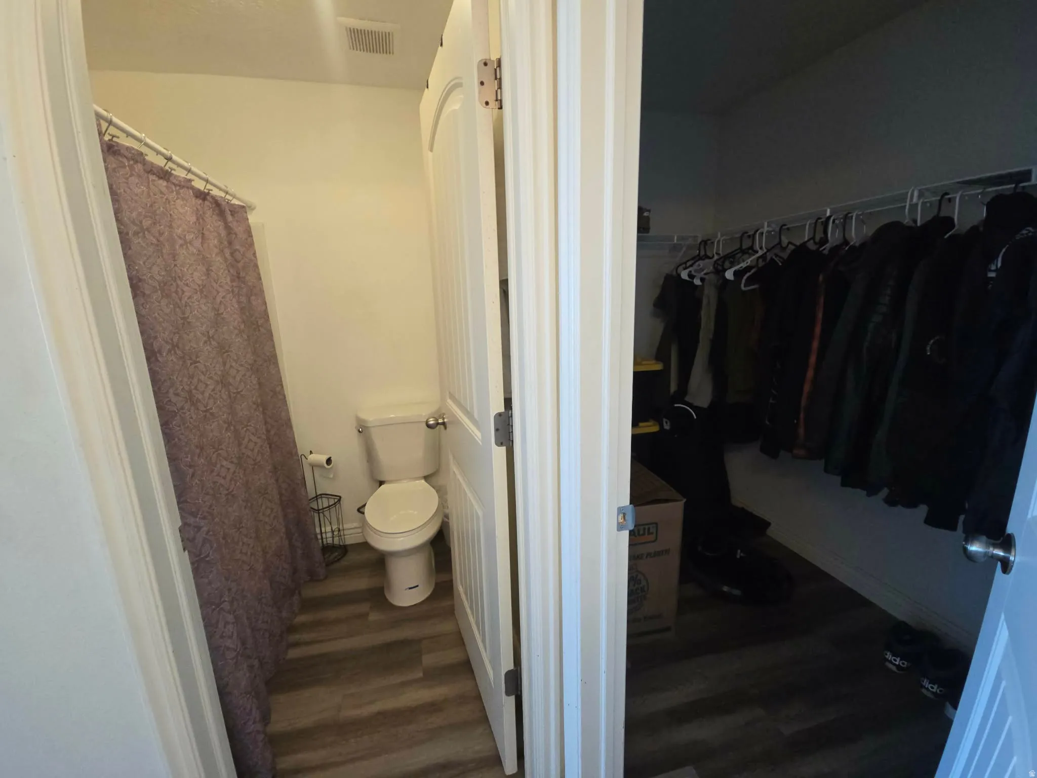 Master bathroom with a shower with shower curtain, a spacious closet, and dark wood-type flooring