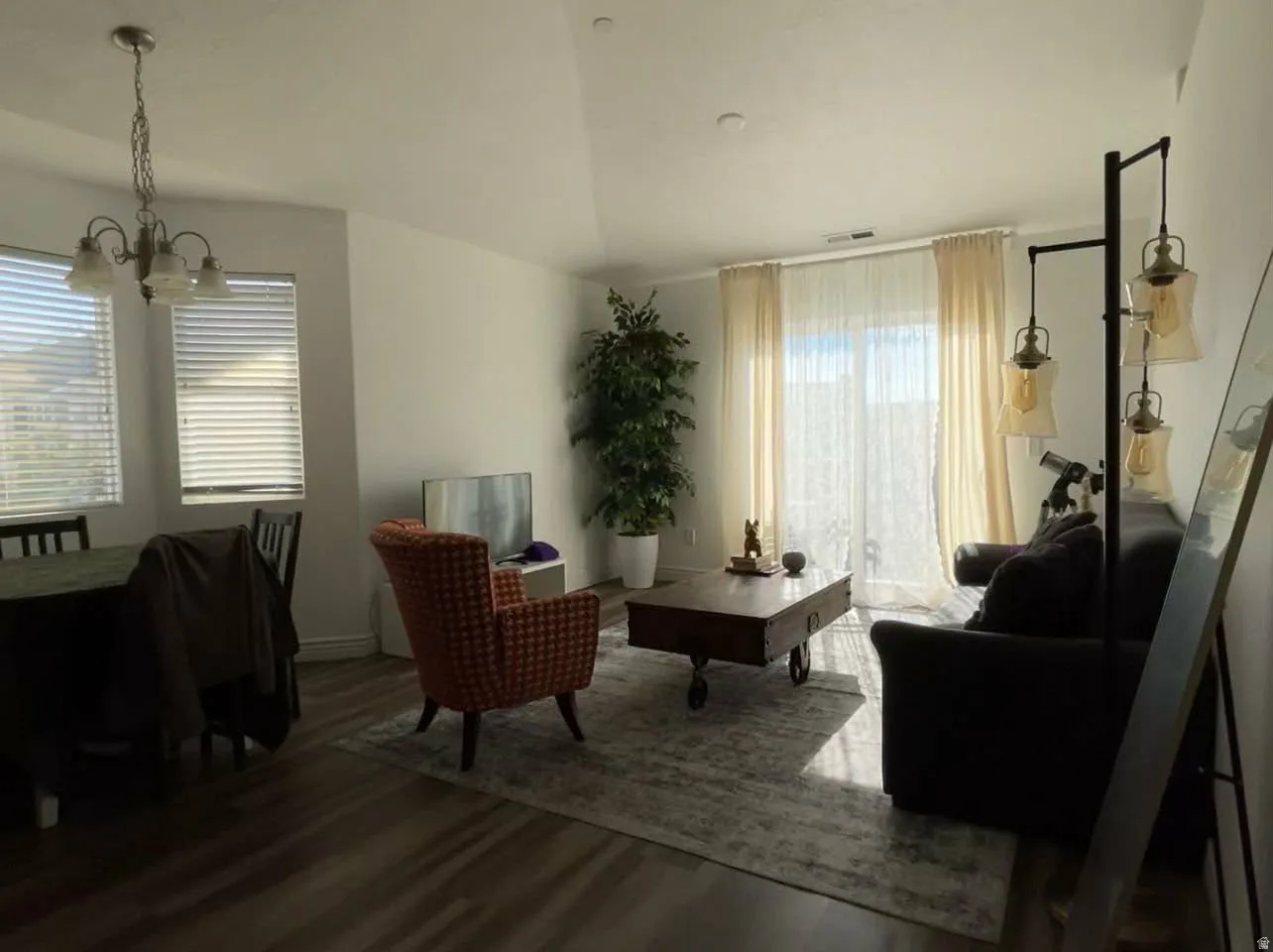 Living area with wood finished floors, vaulted ceiling, and suspended lighting