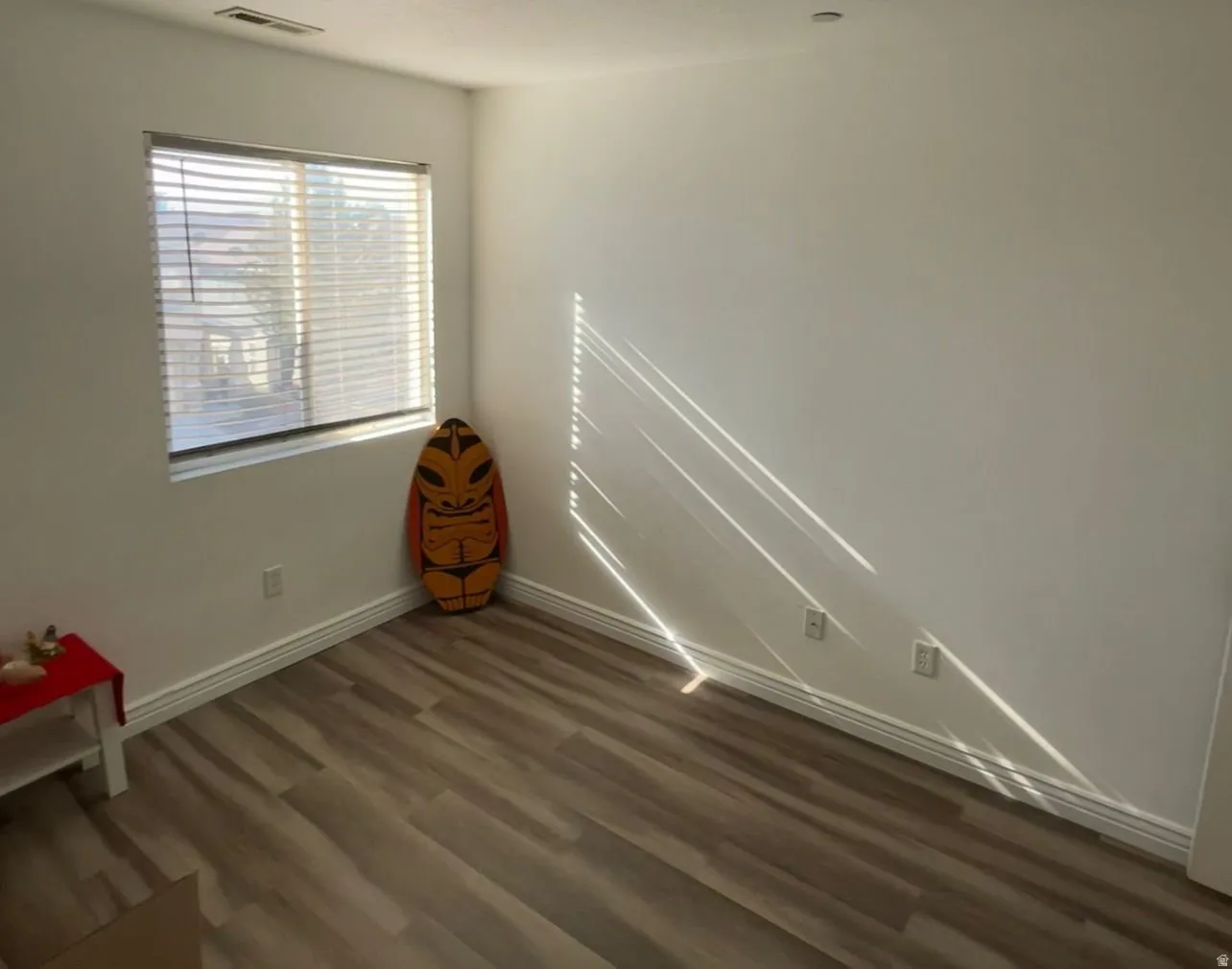 Empty room with dark wood-style flooring and baseboards